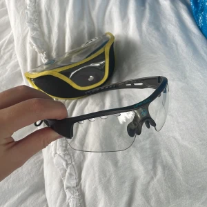 Unihoc sportglasögon grå - Säljer ett par sportiga Unihoc glasögon i svart med blå logga och transparenta. Perfekta för innebandy eller annan sport. Kommer med ett smidigt fodral. 