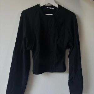 Svart långärmad tröja från 157 - En basic svart långärmad tröja från 157 i storlek XS. Tröjan har rund halsringning och är tillverkad i mjuk bomull, perfekt att matcha med jeans eller kjol. Enkel och stilren design som funkar året runt.