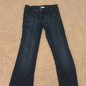 Mörkblå jeans från Gina Tricot, stl 158 - Snygga mörkblå jeans från Gina Tricot med raka ben och markerade sömmar framtill. Hög midja, dubbla knappar och stora fickor framtill ger en cool look. Klassisk femficksmodell i stretchig denim som sitter skönt hela dagen.
