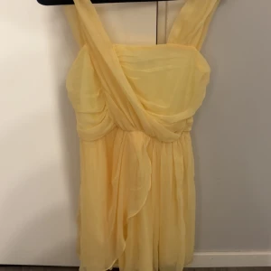 Gul omlottklänning med volang - Superfin gul kortklänning med omlott-detaljer och volang. En jättefin ljusgul klänning som jag själv använt med nerdragna band