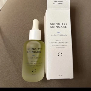 Skincity Algae Therapy Oil 30ml - Skincity Skincare Algae Therapy Oil med mikro- och makroalger. Kommer i en frostad glasflaska med pipett och vit kork. Oljan är ljusgrön och passar för mogen eller torr hud. Förpackningen är stilren och vit.