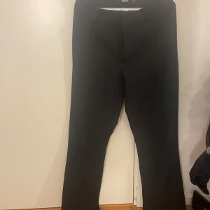 Svarta kostymbyxor från BikBok - Svarta kostymbyxor från BikBok i klassisk rak/bootcut modell. Byxorna har hällor för bälte och stängs med dragkedja och knapp framtill. Perfekta för en clean och stilren look. Materialet känns mjukt och följsamt.
