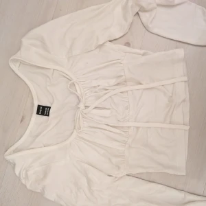 Vit långärmad blus från SHEIN - Supersöt vit blus från SHEIN med långa ärmar och knyt framtill. Toppen har en fyrkantig ringning och lätt rynkade detaljer över bysten. Tillverkad i mjuk viskosblandning som känns skön mot huden. Storleken är petite XXS med den passar som en XS och säkert S