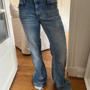 Blå bootcut jeans med fickdetaljer - Snygga blå jeans med bootcut passform och coola fickor. Jeansen har en klassisk femficksdesign, låg midja och är tillverkade i mjukt denim. 