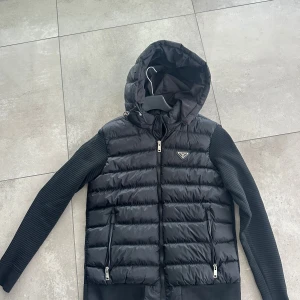 Svart pufferjacka från Prada med huva - En svart cardigan ifrån Prada. Endast använd 1-2 gånger, nästan som ny. Storlek M\L 