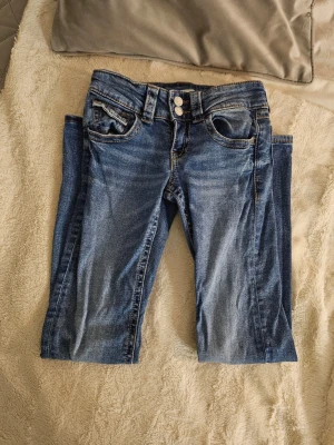 Blå jeans från Gina Tricot, storlek 152 - Snygga blå jeans från Gina Tricot med klassisk femficksdesign och dubbla silverfärgade knappar i midjan. Använda och därför i helt okej skick, därför priset. Bootcut och lågmidjade. Nypris runt 300 kr. Jag har sytt med svart tråd vid blixtlåset pga slitage, se bilder. 💓