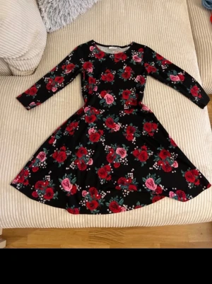 Blommig svart klänning från KappAhl - Supersöt svart klänning från KappAhl med röda och rosa rosor. Passar både Xs och barn med strl 158