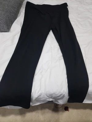 Svarta bootcut byxor - Snygga svarta bootcut byxor med hög midja. De har en klassisk siluett med utsvängda ben och är tillverkade i ett mjukt och stretchigt material som ger en bekväm passform. Perfekta för dig som gillar stilrena och trendiga plagg. Säljer dessa för att föräldrar köpte men de var för stora