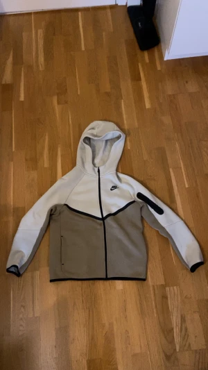 Nike tech zip hoodie/ tjocktröja - XL (passar cirka 158-170 enligt lappen) 158-170 - Snygg och bekväm Nike hoodie i tjockare material, perfekt för höst och vinter. Tvåfärgad design i beige/brun med svarta detaljer, hel dragkedja och huva. Klassisk Nike-logga på bröstet och ficka på armen ger en sportig look.