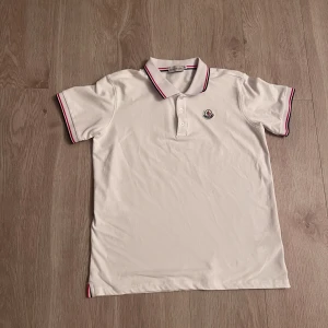 Vit Moncler piké - Hej! Jag säljer en vit Moncler piké som är Använd 1 gång, Storlek M men passar som både M och S