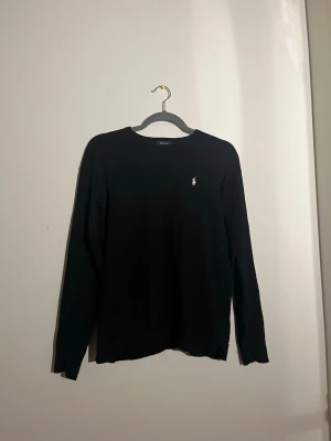 Svart tröja från Polo Ralph Lauren - Säljer en svart stickad Polo Ralph Lauren tröja. Tröjan har något litet hål i halsmudden och ett lagat hål ses på bild! Skriv om ni undrar något!😃