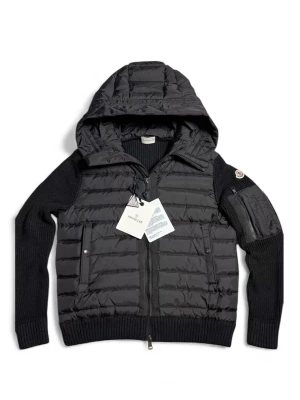 Moncler cardigan jacket (har kvitto) - Svart pufferjacka från Moncler med stickade ärmar och huva. Jackan har quiltad framsida, dragkedja hela vägen, ribbade muddar och en ficka med dragkedja på ärmen. Perfekt för dig som vill ha en snygg och varm jacka med exklusiv känsla.