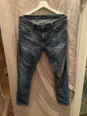 Blå jeans från Nudie Jeans - Snygga blå jeans från Nudie Jeans i med schysst wash och raka ben, dem perfekta jeansen för dig med en archive/grisch stil! Jeansen har normal passform och är tillverkade i slitstarkt bomullsmaterial. Modellen är lean dean med W32/L30