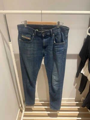 Diesel jeans - Säljer ett par blå Diesel D-Strukt jeans med slim passform och stretch. Klassisk femficksdesign, snygga slitningar och läderpatch med Diesel-logga bak i midjan. Perfekt för dig som gillar stilrena jeans med modern look. Storleken är W33 och L32. Hör av er vid frågor eller funderingar 