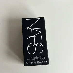 NARS Liquid Blush Orgasm 15ml - Flytande rouge från NARS i färgen Orgasm, en ikonisk persikorosa nyans med gyllene skimmer. Kommer i en stilren, matt glasflaska med svart lock och tydlig NARS-logga. Perfekt för att ge kinderna en fräsch och naturlig glow. Ordinarie 470kr pris 400kr