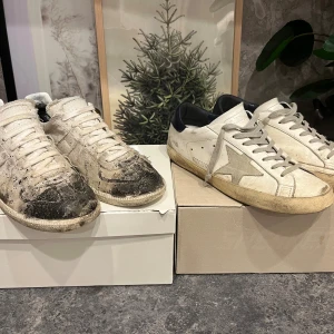 Maison margiela & golden goose - Två par sneakers: Maison Margiela i vitt skinn med svart slitningar och klassisk design, samt Golden Goose i vitt skinn med grå stjärndetalj och svart häl. Båda har snörning, platt sula och vintage-look. Kommer med originalkartonger och dustbags. ett par för 1250kr eller båda för 2300 går definitivt att göra dom snyggare