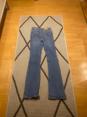 Levi's blå bootcut jeans - Säljer ett par klassiska blå Vero Moda  jeans med bootcut-snitt. Materialet är slitstarkt jeans och passformen är normal med något utsvängda ben. Perfekt för dig som gillar retrostil och vill ha ett par snygga jeans.