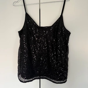 Svart paljettlinnetopp med smala axelband - Säljer en svart linne-topp med smala axelband från HM i storlek M. Perfekt linne för nyår 🤩