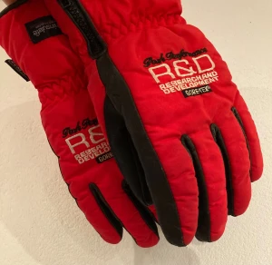 Peak Performance Gore-Tex handskar - Säljer ett par röda Peak Performance R&D handskar med svart detalj och broderad logga. Utrustade med Gore-Tex och Thinsulate för extra värme och skydd mot väder. Handskarna har dragkedja på sidan för bra passform.