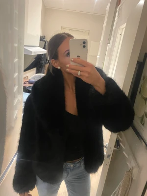 Svart pälsjacka med bred krage - Säljer en svart pälsjacka med bred krage och lång ärm. Jackan har en fluffig och lyxig känsla, perfekt för dig som vill sticka ut. Modellen är lite boxig och ger en cool siluett. Passar dig som gillar statement-plagg och vill hålla dig varm med stil. Helt slut såld från stockh LM studio nypris 3000