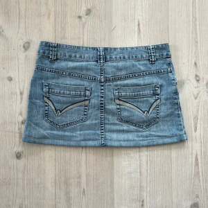 Blå lågmidjad jeanskjol  - Ljusblå lågmidjad jeanskjol från Flash Jeans i storlek 38. Tvärs över midjan är det 40 cm och den är 30 cm lång (längs med sidan). Fint skick. Använd gärna köp nu!