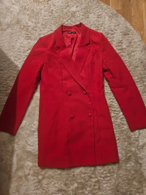 Röd kavaj från SHEIN, strl M - Snygg röd kavaj från SHEIN i storlek M (EU 38). Dubbelknäppt design med matchande röda knappar och klassisk krage. Långärmad och med slät, stilren look som ger en cool vibe. Perfekt för dig som vill sticka ut med färg.