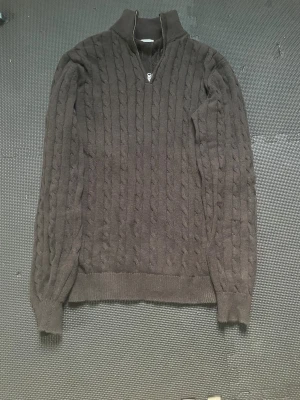 Svart kabelstickad tröja John Henric - Svart kabelstickad tröja från John Henric med halv dragkedja och ståkrage. Tillverkad i 100% bomull, perfekt för kyliga dagar.  Frågor om varan svaras i DM 😁