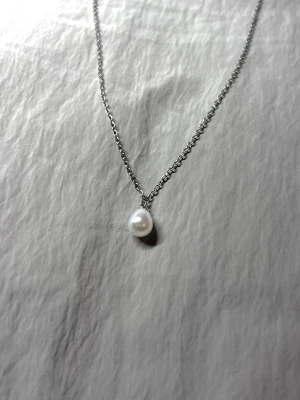 Quiet Pearl - Halsband i rostfritt stål med ett droppformat pärlhänge.