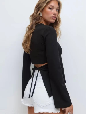 Svart blus med öppen rygg - tie back long sleeve top från Ginatricot. Använd 1 gång på ett event! Har dessutom en vit som aldrig använts och med prislappen kvar. Säljs på grund av flyttstädning.  