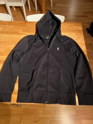Polo Ralph Lauren hoodie - Snygg Ralph lauren zip hoodie i storlek 170 cm och färgen svart. Inget slitage på tröjan. Hör av dig om du har frågor.