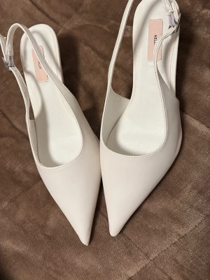 Vita kalk med spetsig från Nelly - Hej säljer ett par vitta klackar från Nelly med spetsig tå och låg klack. Skorna har en öppen häl med justerbart spänne och är gjorda i syntetmaterial. Seljer för har hittat ett par andra skor som passade mig bättre dom har aldrig använts bara typ en gång för att testa dom. Priset kan diskonteras 