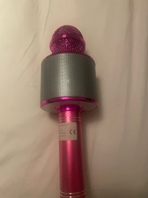 Trådlös karaoke-mikrofon med högtalare - Rosa trådlös karaoke-mikrofon med inbyggd högtalare och kontrollpanel. Flera funktioner som volymkontroll, inspelning och låtval. Perfekt för fester och hemmabruk. Musik kopplas till inbyggda högtalare via bluetooth 