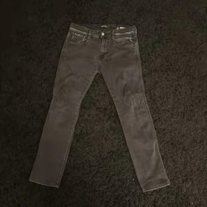 Replay Anbass svarta jeans - Svarta Replay Anbass jeans med klassisk femficksdesign och snygga detaljer på bakfickorna. Jeansen har en slim passform och är tillverkade i stretchigt jeansmaterial för extra komfort. Perfekta för dig som gillar stilrena och moderna jeans.