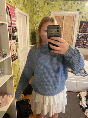 Ljusblå stickad tröja - Mysig ljusblå stickad tröja med grovstickat mönster och rund hals. Tröjan har långa ärmar och ribbade muddar vid ärmslut och nederkant. Perfekt för lager-på-lager och enkel att matcha med olika stilar.