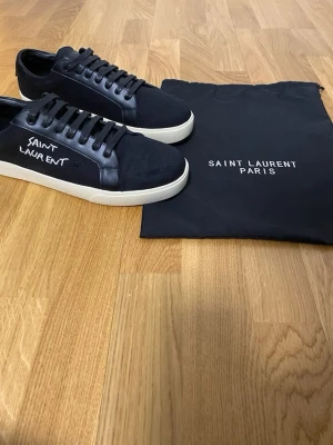 Svarta Saint Laurent sneakers - Säljer nu dessa oanvända Saint Laurent skor. Dom är helt oanvända och är väldigt stilrent skick. Dustbag och kvitto följer med. Skorna är i storlek 43 men passar även storlek 42. Priset kan alltid diskuteras, ställ även gärna frågor! 😊✨