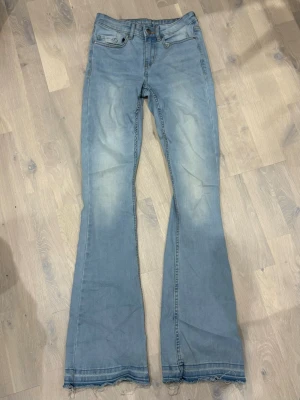 Ljusblå bootcut jeans - Snygga ljusblå bootcut jeans med rå, fransad kant nedtill då dom är uppsprättade . Klassisk femficksmodell och normal midja. Jeansen har en tvättad look och är tillverkade i mjukt denimtyg, perfekta för en avslappnad stil.