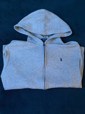 Ralph Lauren Zip tröja - Strl XL i barn vilket då översätts till xs dom bäst. Säljer denna grå RL tröjan eftersom den inte längre passar. Den är i okej-bra skick med defekt vilket är ett litet ihopsytt hål på vänster ficka men också fått lite smått blå färg på armen vilket knappt går och se längre                      Priset är inte fast!! Går att förhandla om 