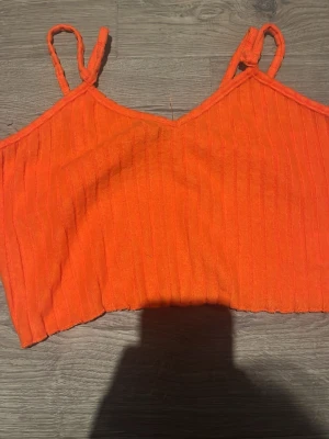 Orange ribbad linnetopp från SHEIN - Trendig orange linnetopp från SHEIN med smala axelband och ribbad struktur. Toppen är croppad och har en enkel, stilren design som passar perfekt till jeans eller kjol. Perfekt för varma dagar och snygga outfits.