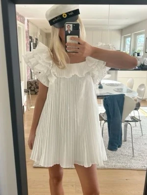 Vit plisserad kortklänning med volang -  Sjukt eftertraktad och populär klänning från Zara 💓Så så fin att ha på studenten!! 💓  kontakta vid frågor annars är det bara att klicka på köp!! Sista bilden är min egna💓