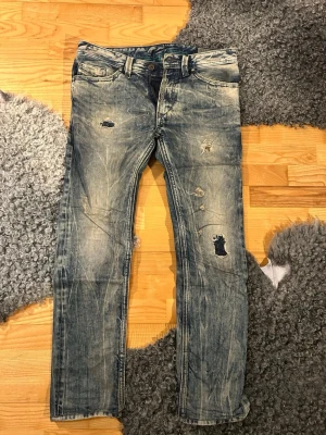 Blå slitna jeans från Diesel - Säljer ett par blå jeans från Diesel med slitna detaljer, riktigt schysst tvätt. Väldigt ovanlig modell. Storlek: 29/30. Fråga gärna om fler bilder, mått med med!🤝🏻✌🏼✨💫
