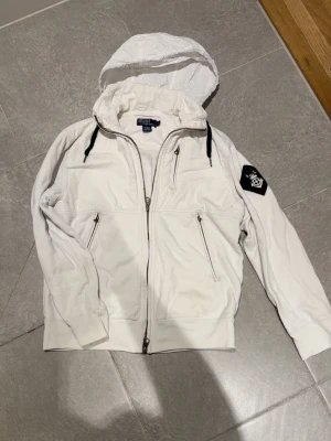 🤍 Polo Ralph Lauren vit jacka med huva - Snygg Polo Ralph Lauren jacka i vitt med huva. Fräsch, sportig och lätt att bära – perfekt för vår/sommar eller som lager på lager. En stilren jacka som sticker ut och ger en exklusiv look.