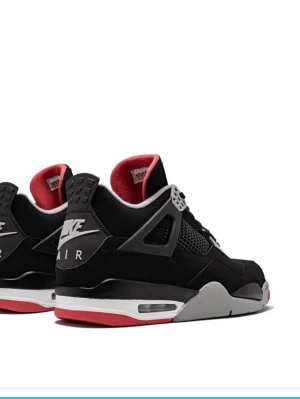 Nike Air Jordan 4 Black/Red sneakers - Grymma Nike Air Jordan 4 sneakers i svart mocka med röda och grå detaljer. Klassisk siluett med meshpaneler, snörning och ikoniska Jumpman-loggan på plösen. Snygg kontrast mellan svart ovandel, grå sula och röd yttersula. Perfekta för dig som vill sticka ut.