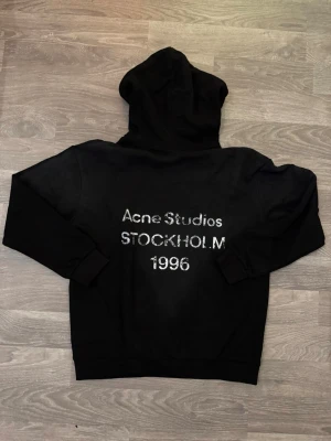 Acne Studios Hoodie - En svart Acne Studios hoodie med texten Acne Studios Stockholm 1996 på baksidan av hoodien. kvitto finns.