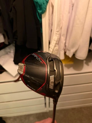 TaylorMade Stealth 2 Driver - Säljer en TaylorMade Stealth 2+ driver med svart och röd design. Klubban har en stor klubbhuvud i kolfiber och metall, samt justerbar vikt. Slagytan är brunröd med vita markeringar. Perfekt för dig som vill ha extra längd och precision på golfbanan. Ventus TR 5-5 skaft stiff.    Jag är ute efter att byta mot en mini driver jag kan även lägga till mellanskillnad