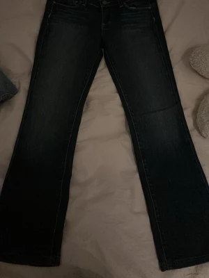 Mörkblå bootcut jeans - Snygga mörkblå jeans med bootcut passform och klassisk femficksdesign. Jeansen har en rak siluett upptill och blir vidare nedtill, vilket ger en avslappnad men ändå stilren look. Perfekta till sneakers eller boots.