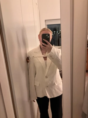 Vit kavaj med klassisk passform - Snygg vit kavaj med klassisk krage och knäppning framtill. Kavajen har långa ärmar, två fickor med lock och en stilren design. Perfekt för dig som vill ha en fräsch och clean look. Nypris 899kr