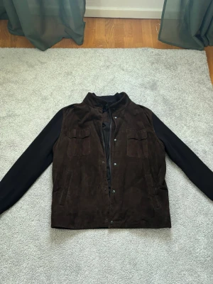 Brun mockacardigan med svarta ärmar - Snygg cardigan i brun mocka med svarta tygärmar från Massimo Dutti. Perfekt för dig som vill ha en unik och stilren look. Är storlek XL men passar mer som L.                                                   Bara att höra av sig vid eventuella frågor!