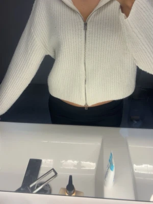 Vit ribbstickad ziptröja - Säljer en krämvit ribbstickad tröja med dragkedja framtill och hög krage. Tröjan har en croppad passform och långa ärmar. Perfekt för lager på lager och enkel att styla till olika outfits.💕kan användas som tröja och jacka 