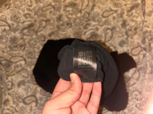 Svart Burberry sweatshirt  - Svart sweatshirt från Burberry i storlek XL med en stor beige patch framtill med Burberry-logga och globmotiv. Tröjan har rund hals och ribbade muddar. Materialet är mjukt och känns som bomull, perfekt för dig som gillar stilrena designer med tydlig branding. Står storlek XL men sitter som M