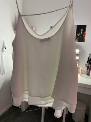 Vit linnetopp med dubbla lager - Säljer en vit linnetopp med tunna axelband och snyggt fall. Toppen har dubbla lager i ett lätt och luftigt tyg som ger en cool och flowy känsla. Perfekt för varma dagar och enkel att matcha med jeans eller kjol.